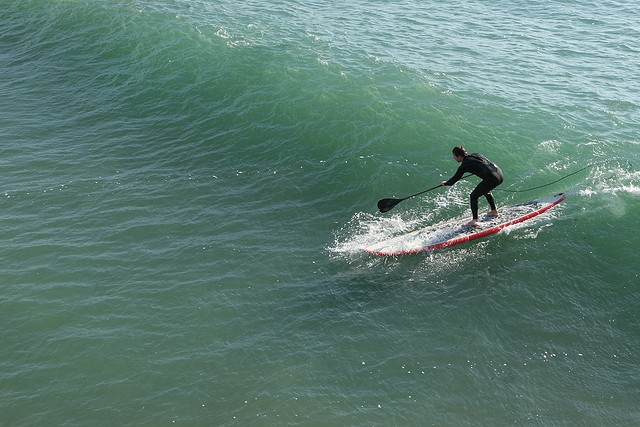 cogiendo una ola practicando paddle surf
